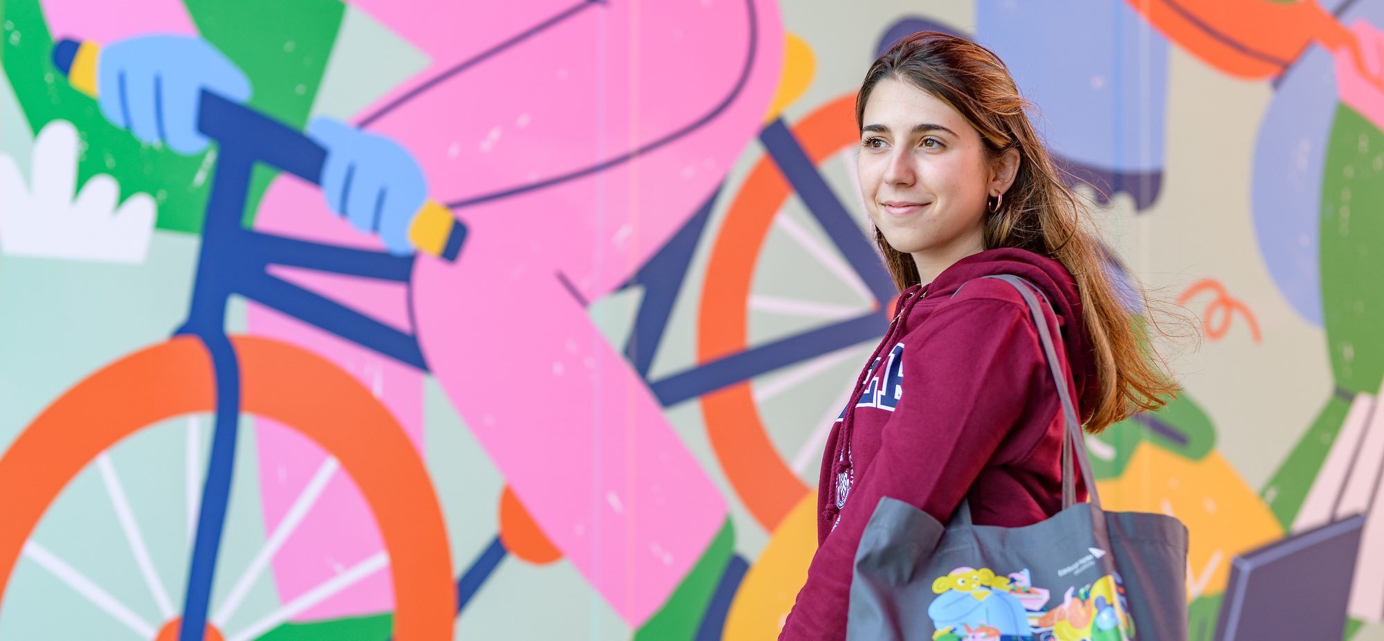 Student standing in front of a colourful mural